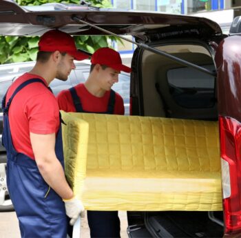 Günstig umziehen in Cottbus: Umzugshelfer laden ein gelbes Sofa in einen Transporter