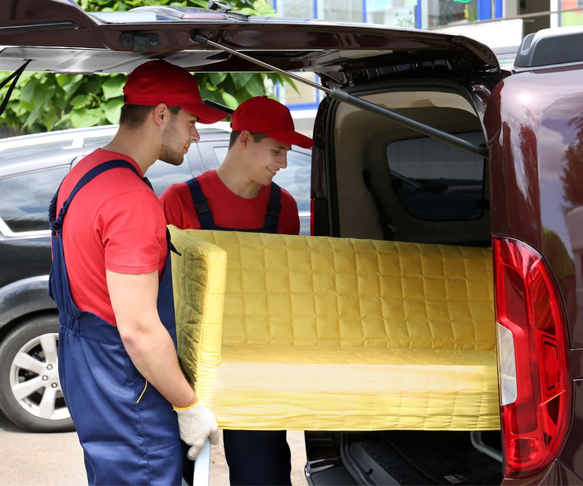 Umzugshelfer laden ein gelbes Sofa in einen Transporter – Preiswert umziehen Cottbus