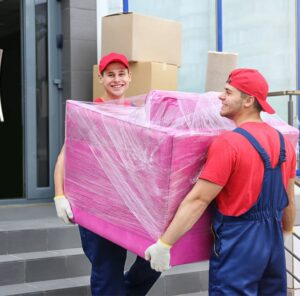Zwei Umzugshelfer tragen ein in Folie gepacktes Möbelstück – Umzug in Cottbus