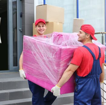 Zwei Umzugshelfer tragen ein in Folie gepacktes Möbelstück – Umzug in Cottbus