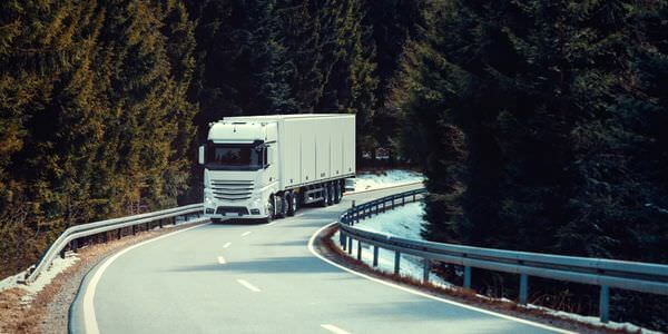 Klaviertransport Cottbus: Lkw fährt auf einer kurvigen Straße durch den Wald
